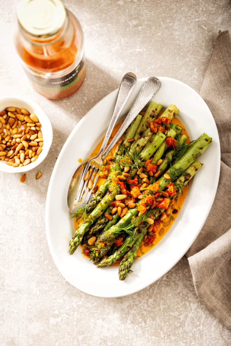 Gegrilde groene asperges met wortel-knoflookjus, dille en pijnboompitten