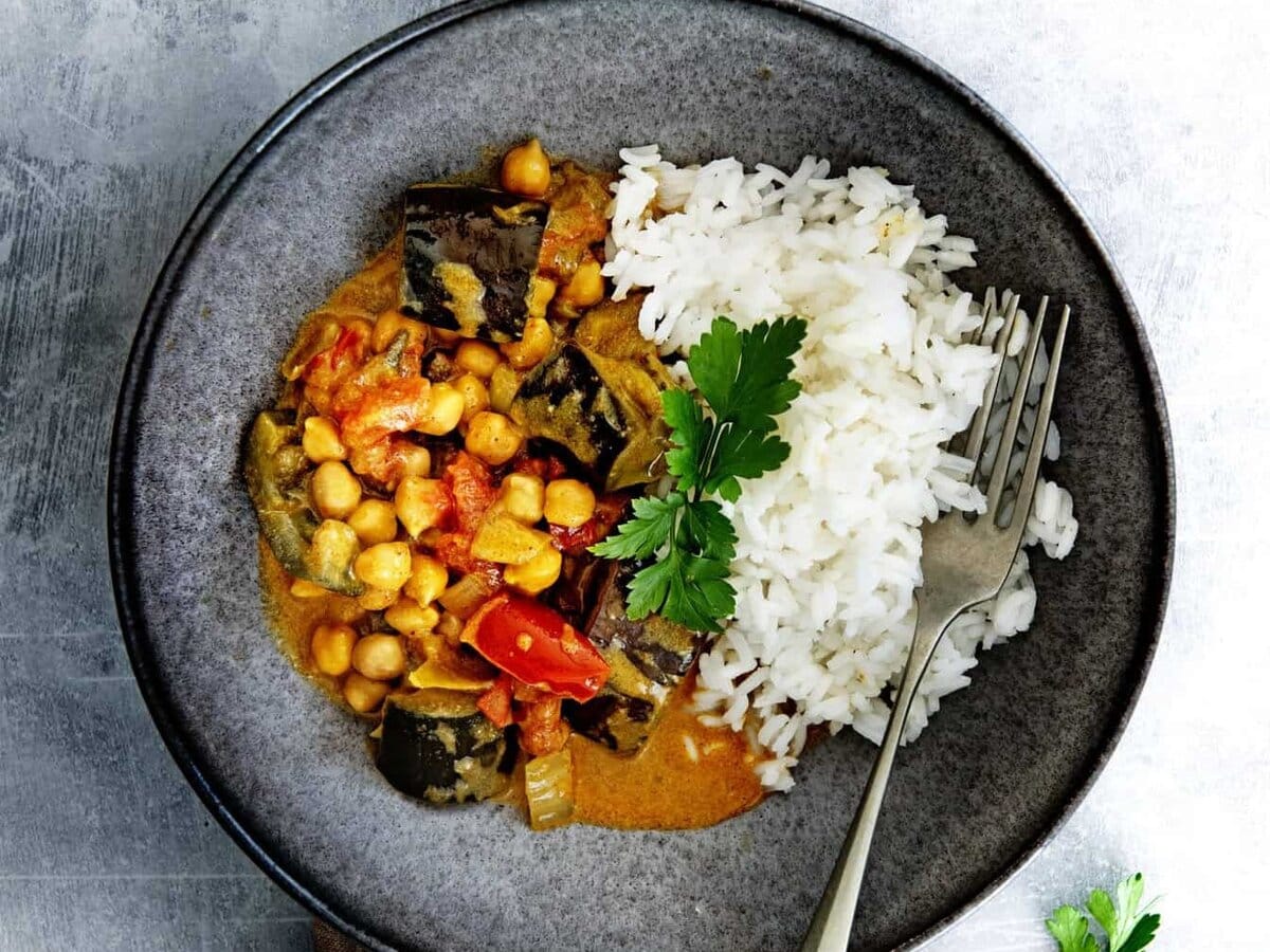 Auberginecurry met kikkererwten in een bord met lepel