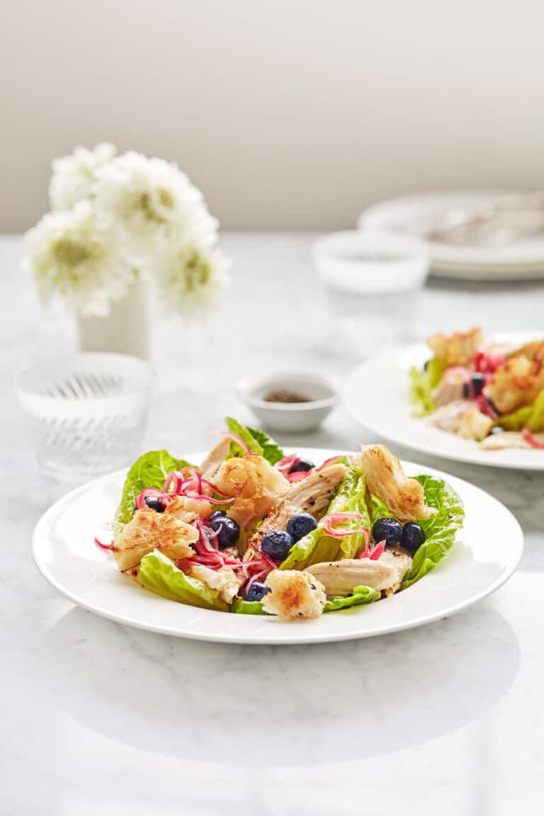 Salade met kip, croutons, ingelegde blauwe bessen en rode ui