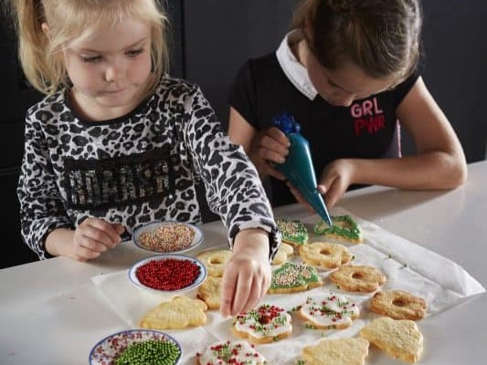 kinderen versieren kerstkoekjes op aanrecht
