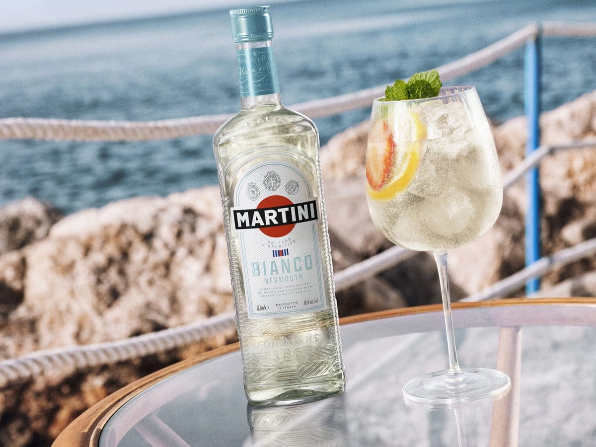 Bianco spritz in een glas en fles MARTINI op een tafel bij de zee