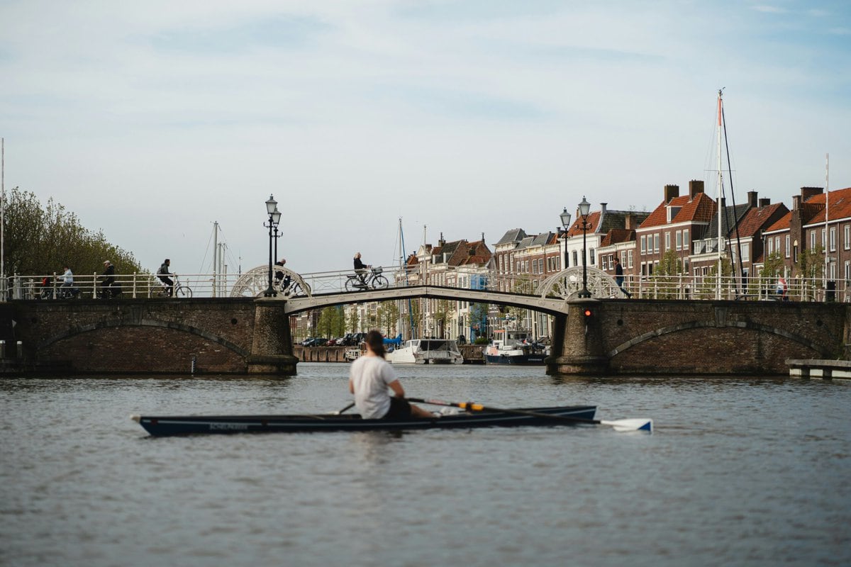 Man in een roeiboot voor de Spijkerbrug in Middelburg