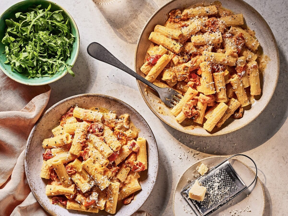 Twee borden pasta met geroosterde tomaat, knoflook en mascarpone met parmezaan erover