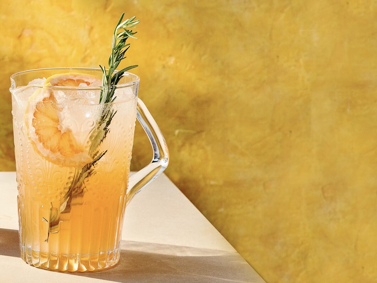 Pitcher met rozensiroop, grapefruit, vlierbloesem en gin met een takje rozemarijn