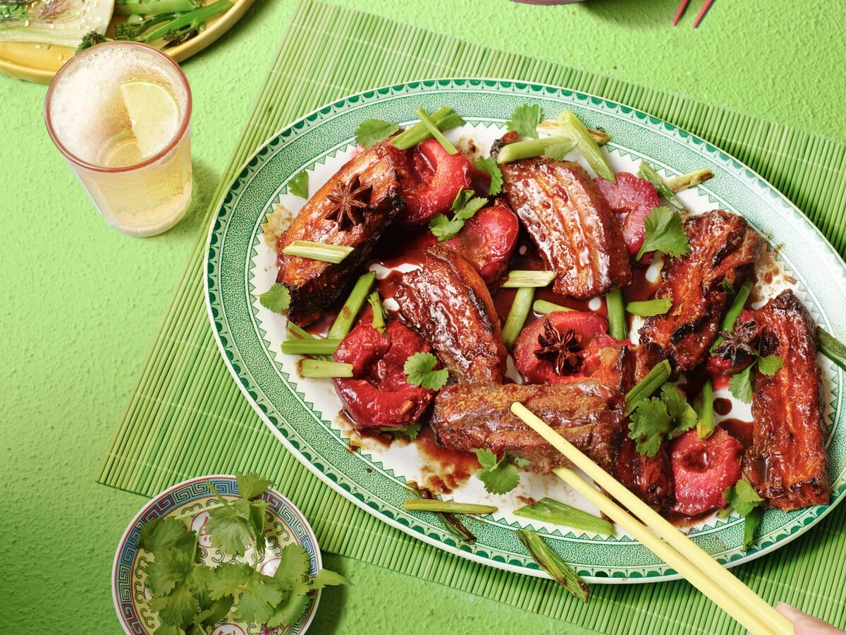 Sticky buikspek gemarineerd in een five-spice sausje met gember, geserveerd met pruimen en koriander