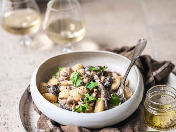 bord gnocchi met bospaddenstoelen en truffel en glazen wijn
