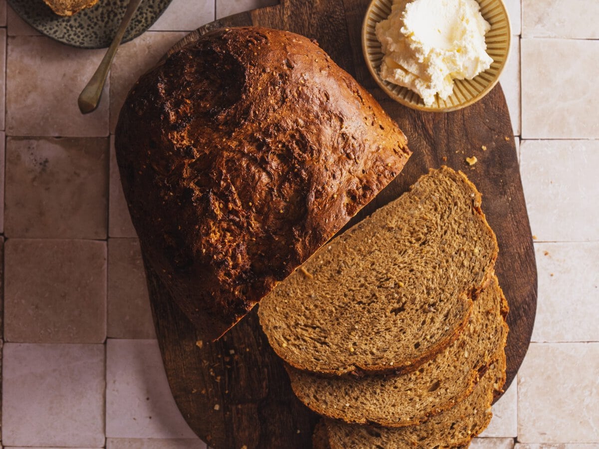 Aardappelmeergranenbrood met boter op een plank