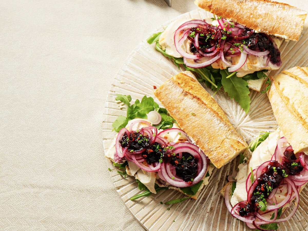 Drie broodjes met kalkoenfilet, spicy bosbessenspread, rode ui, rucola en bieslook
