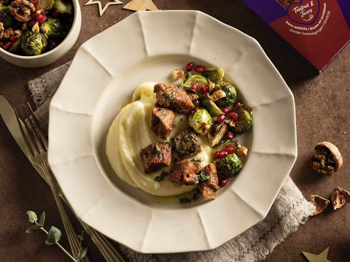 Kaas-aardappelpuree met daarop vegetarische steakpuntjes en spruitjes met wat granaatappelpitjes