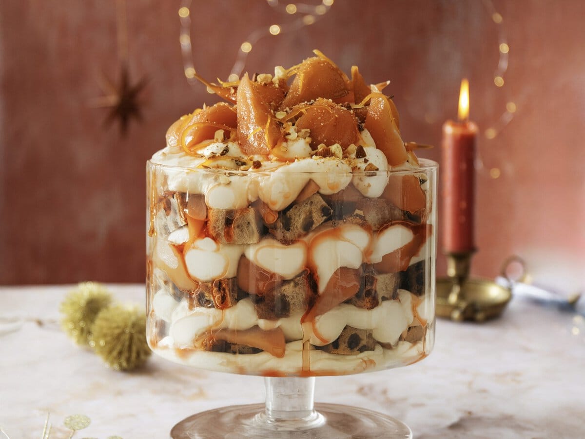 Trifle met laagjes feeststol, stoofperen, room en theesiroop met bovenop witte chocolade en amandelen