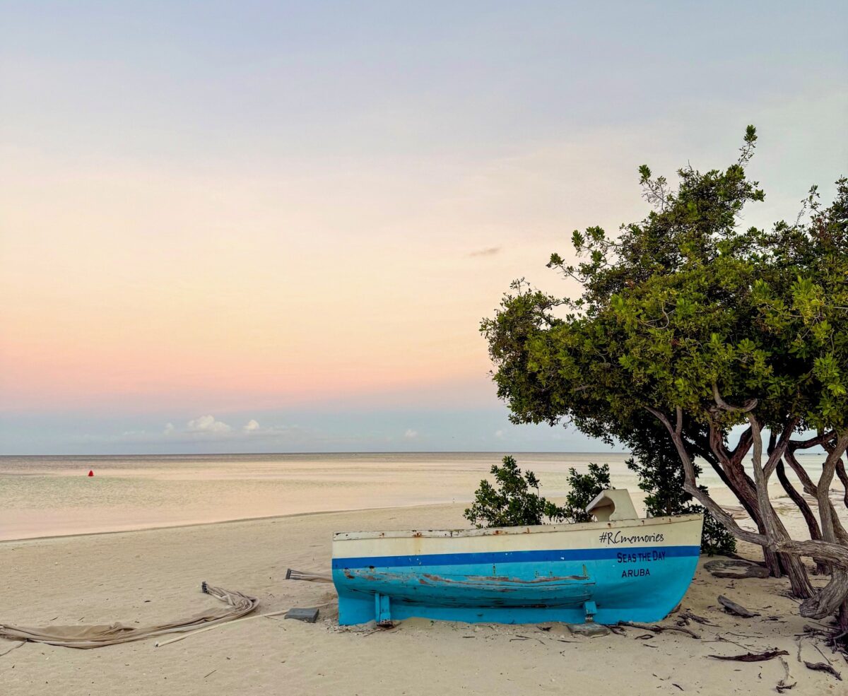 Blauwe boot op Palm Beach Aruba tijdens zonsopkomst