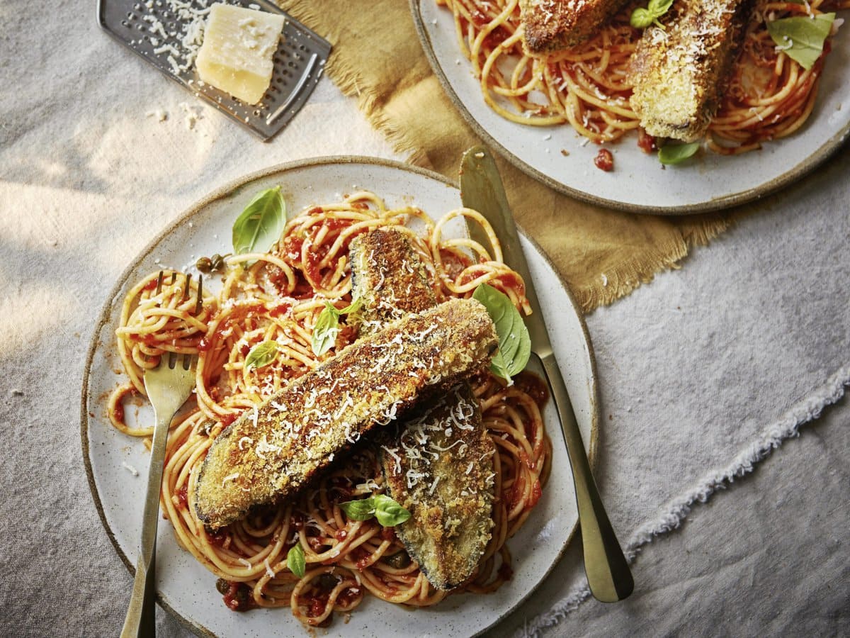Spaghetti met rode saus met daarop gefrituurde aubergine, basilicum en parmezaan