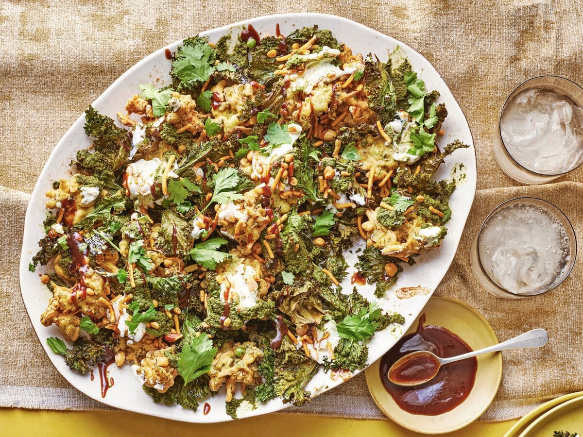Boerenkoolchaat met pakora’s, gebakken boerenkoolbladeren, kruidenchutney en verse toppings geserveerd op een groot bord