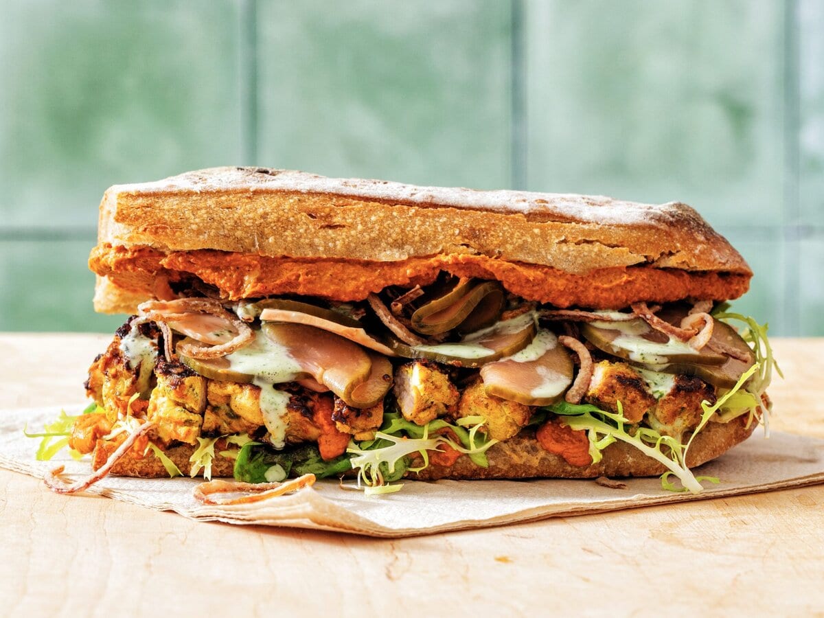 Sandwich met butter-chicken, yoghurt, ingelegde groenten en gemengde sla