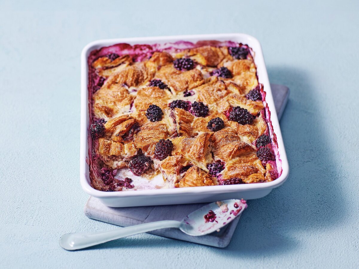 Gekaramelliseerde croissantwentelteefjes in een ovenschaal met bramen