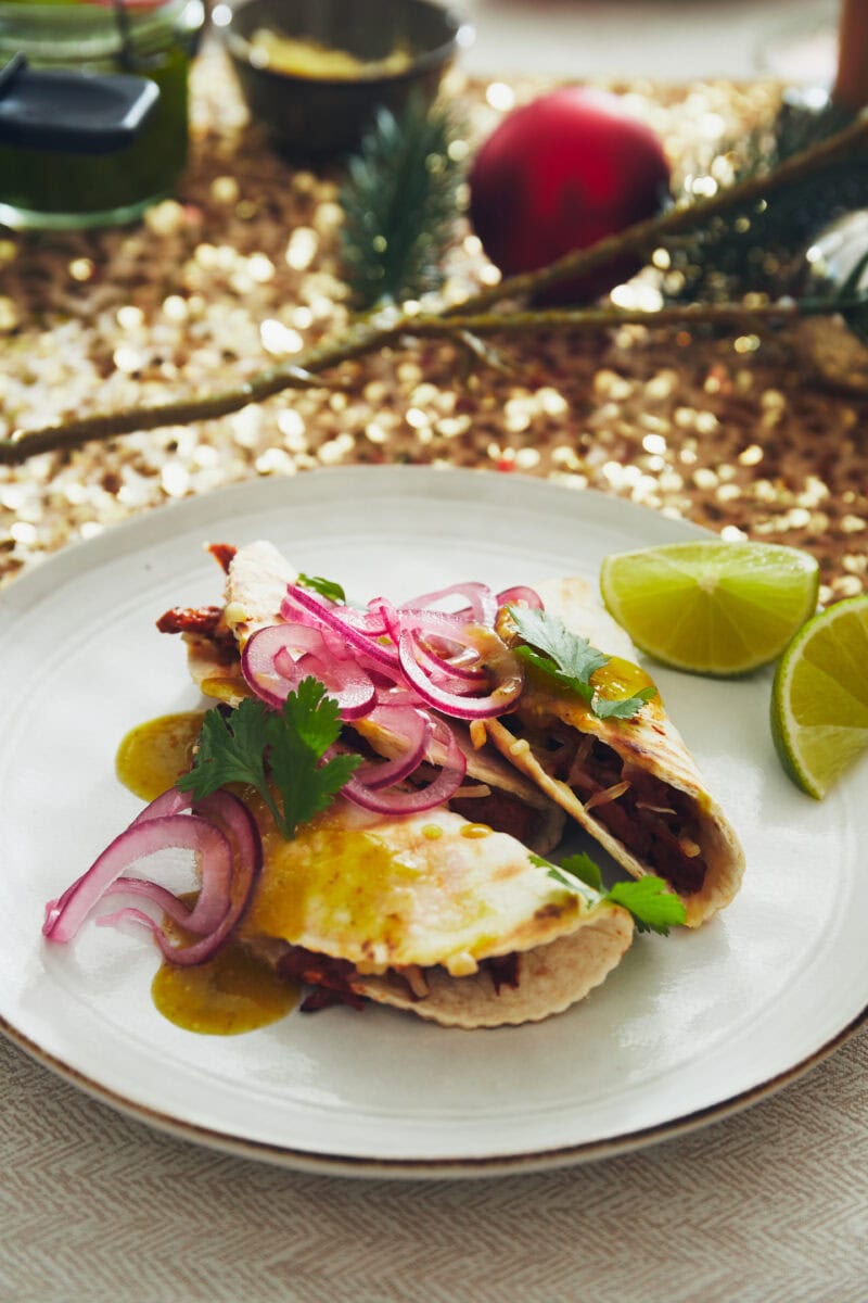 Twee empanada's met vega pulled BBQ, groene salsa, rode ui, koriander en limoen