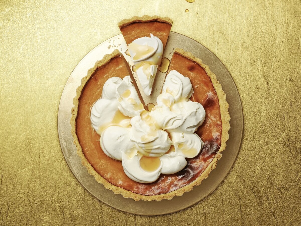 Pumpkin pie met slagroom en ahornsiroop erop met een stukje eruit gesneden