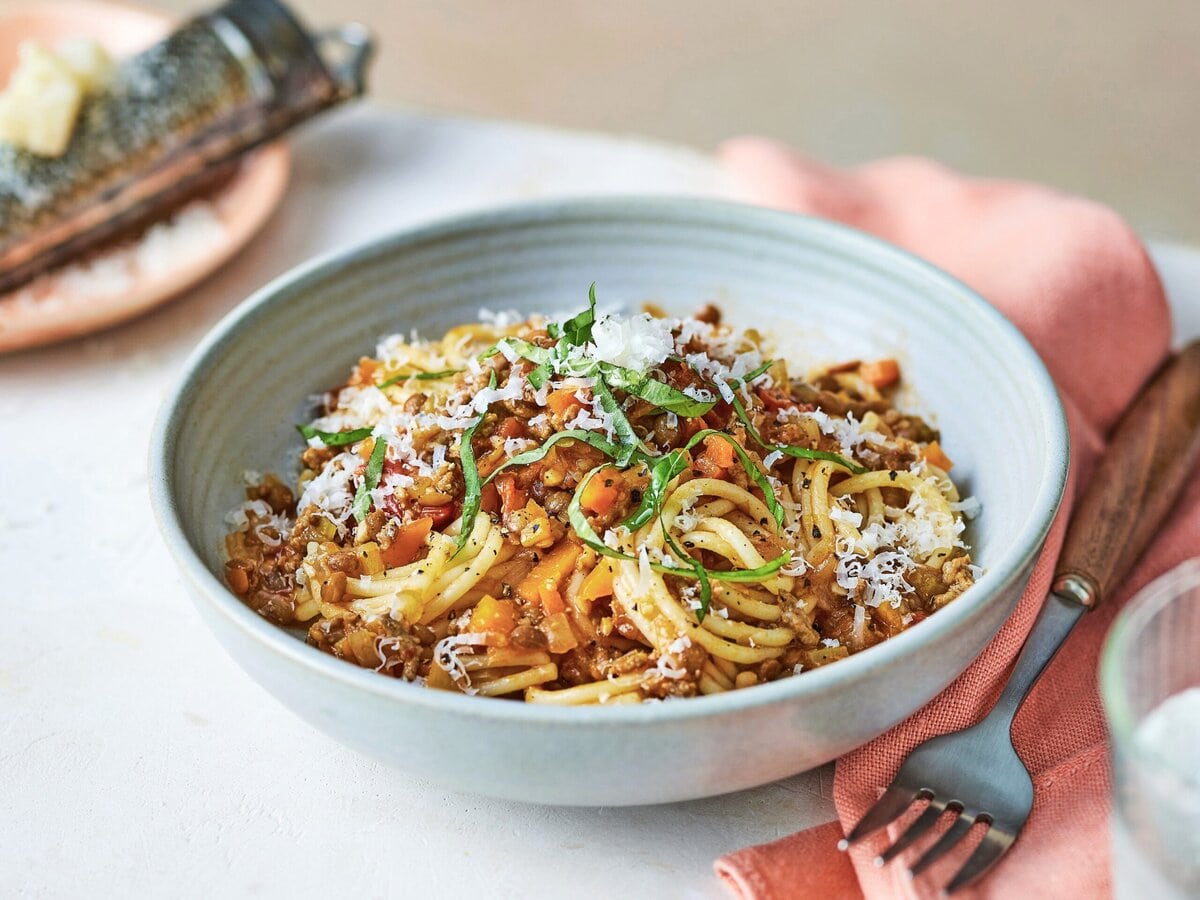 Spaghetti bolognese met linzen met daarover basilicum en Parmezaanse kaas