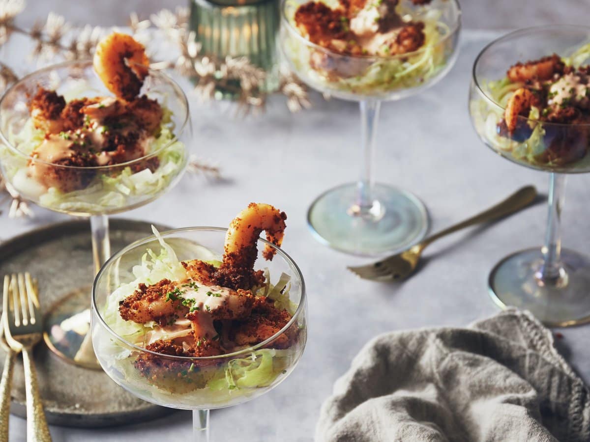 Vier cocktailglazen met avocado, ijsbergsla, texmex crispy garnalen en een sausje