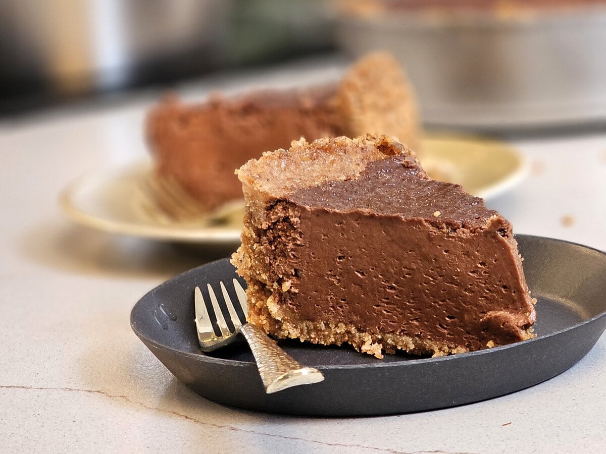 Chocoladecheesecake met biscuitbodem op een bord met vork