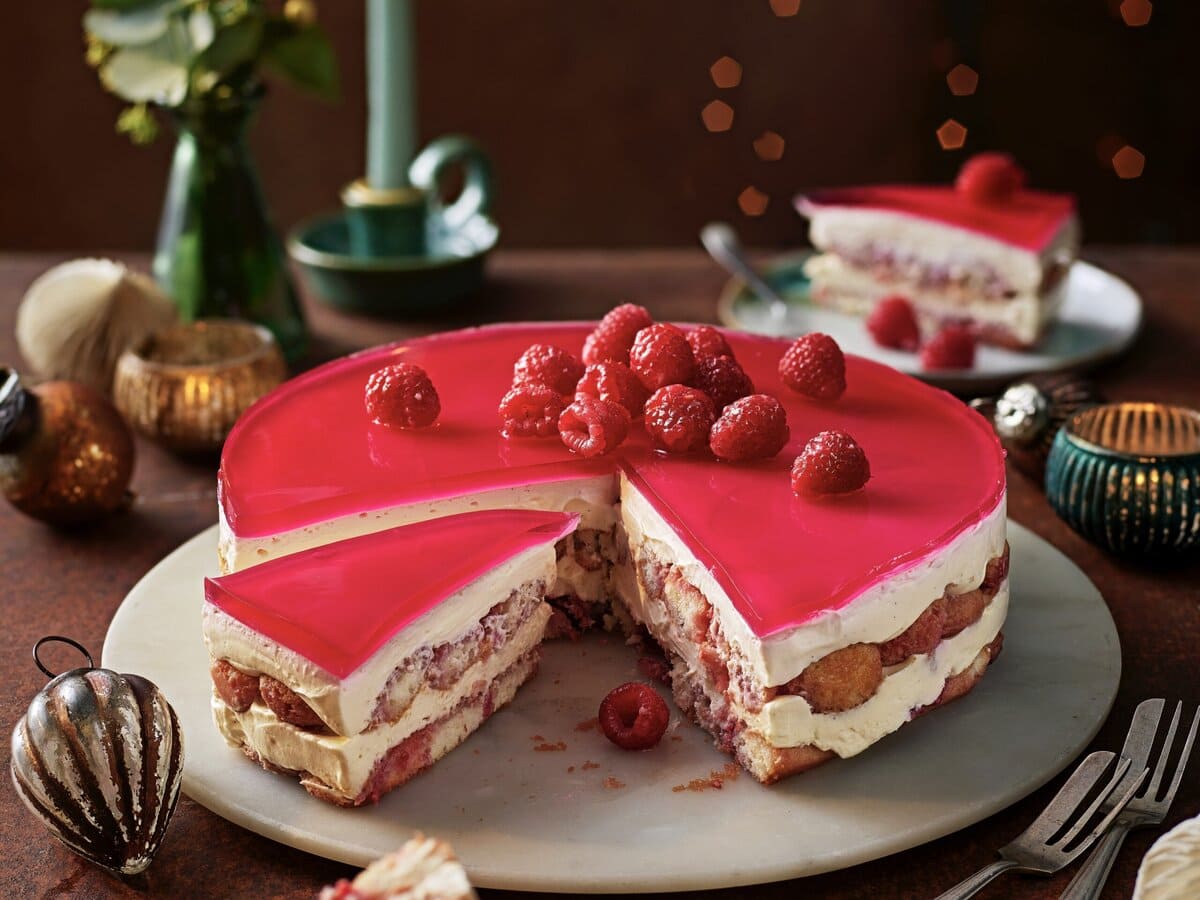 No-bake frambozentrifletaart met frambozen bovenop en een stukje eruit