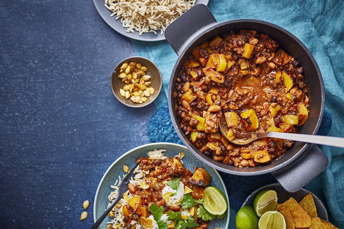 Smoky pompoenchili geserveerd met onder andere rijst, tortillachips, koriander, zure room en limoen