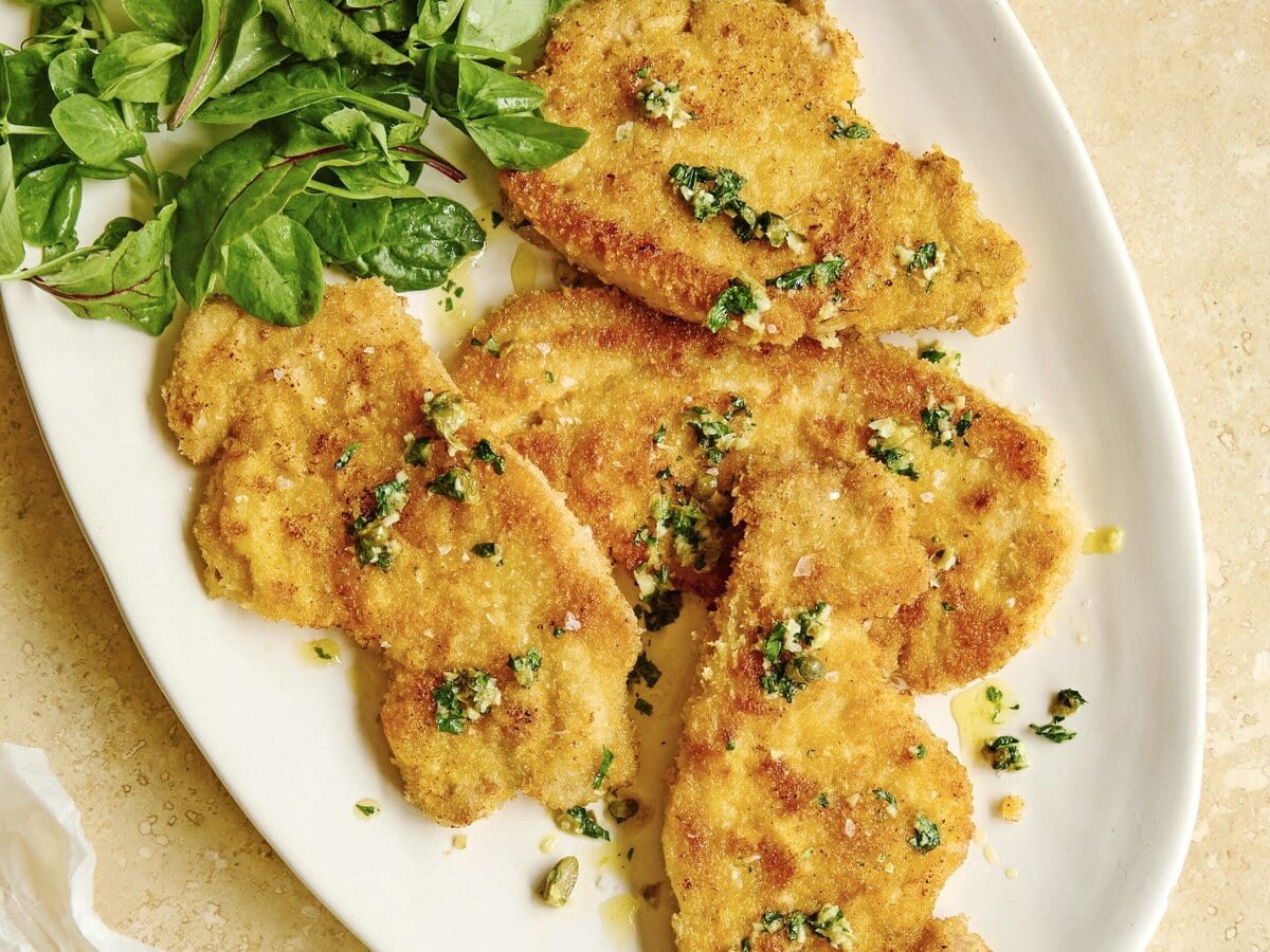 Varkensschnitzel met citroen-kappertjesboter en daarnaast een salade en gekookte krieltjes