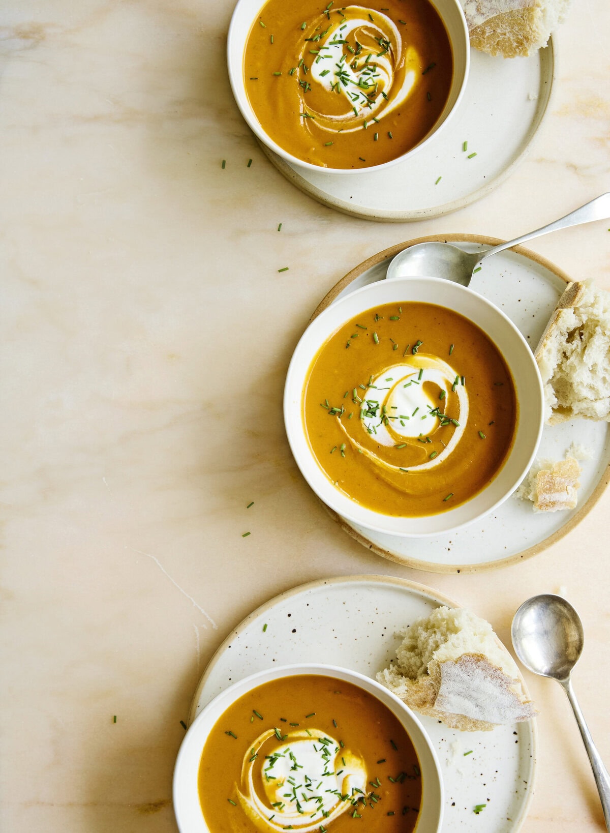 Drie koppen zoete-aardappelsoep met chipotle, geserveerd met zure room en bieslook