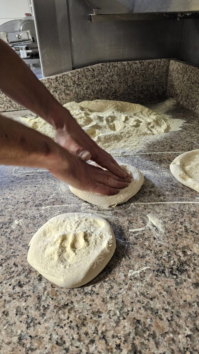 Pizzaiolo maakt pizzadeeg bij een pizzeria