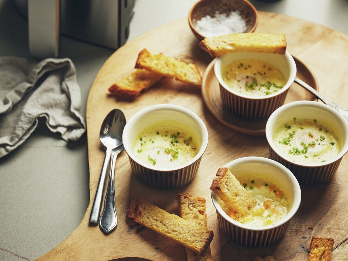 4 cocottes gevuld met baked eggs en geserveerd met knapperige croutons