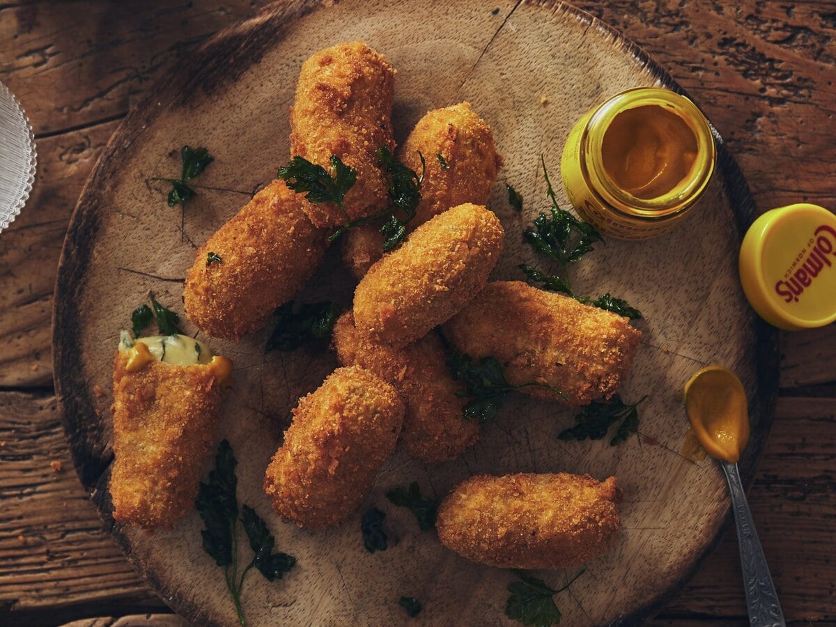 Cheddarkroketjes met als vulling gele mosterd en spinazie, met daarnaast een bakje mosterd en peterselie