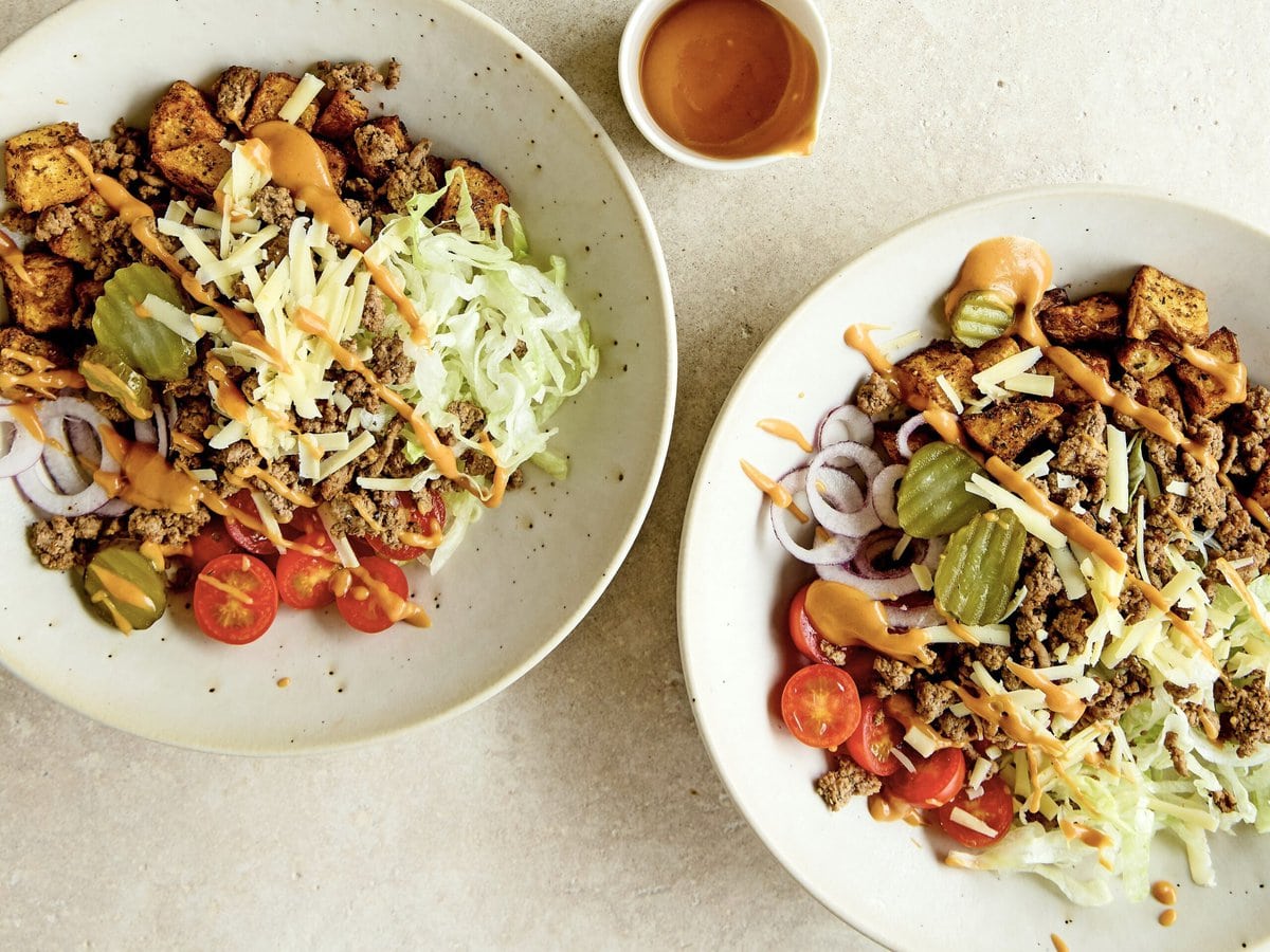 Twee cheeseburgerbowls met gehakt, ijsbergsla, augurk, tomaat, rode ui en cheddar