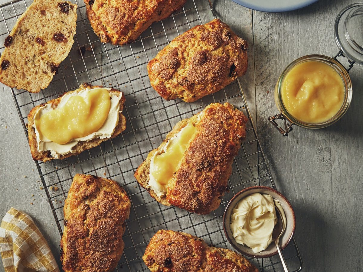 Kaneelscones op rooster waarbij twee zijn doorgesneden en besmeerd met appelcurd