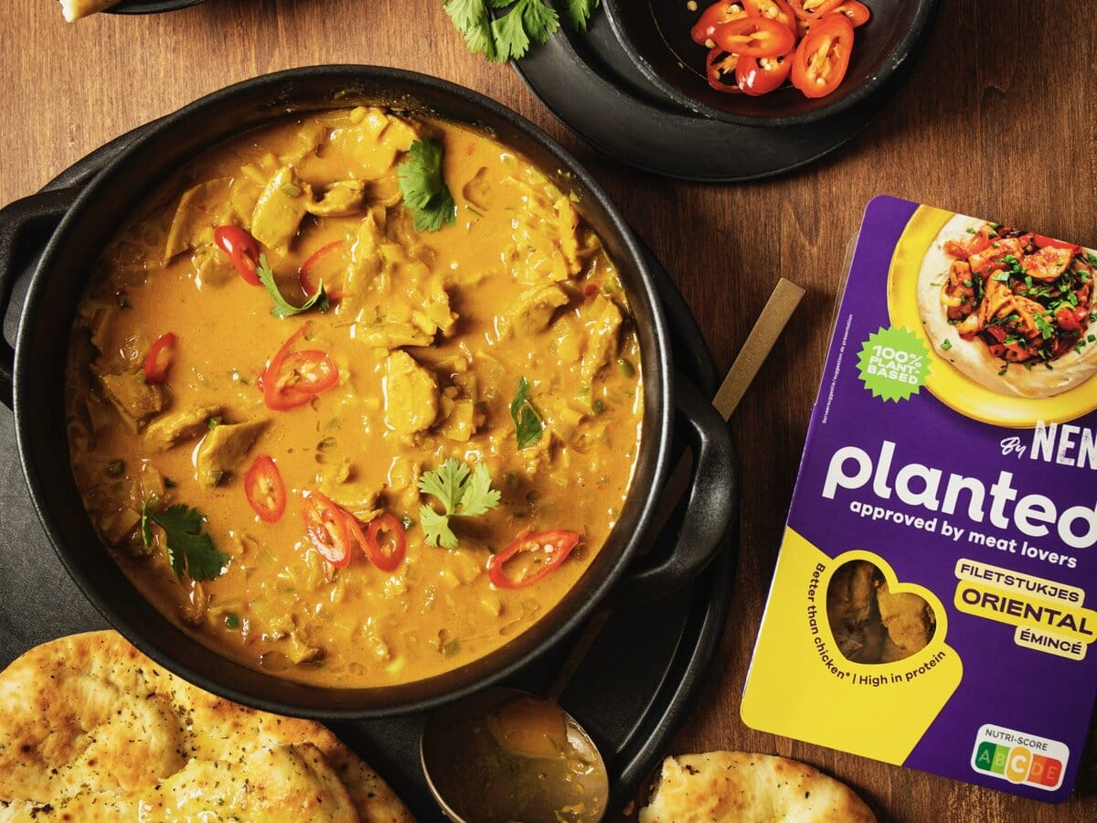 Kipcurry met kokosmelk, koriander en rode peper, geserveerd met naan en daarnaast een pakje Planted filetstukjes