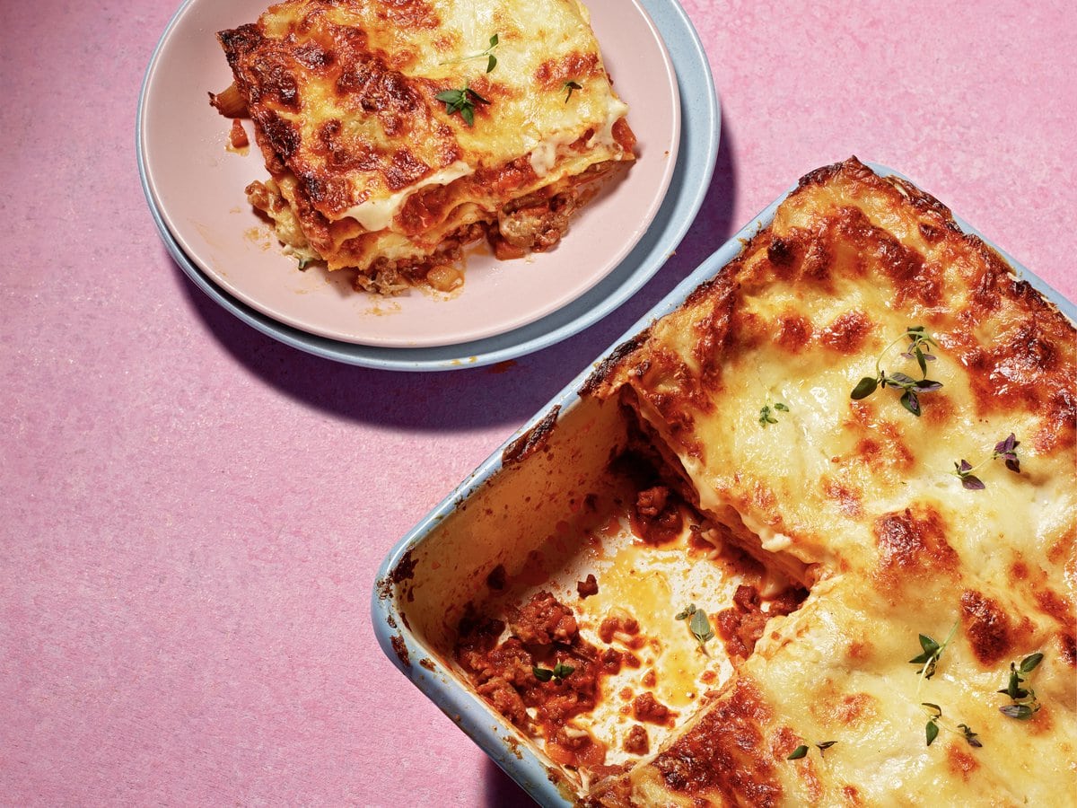 Lasagne met ‘nduja en Italiaanse braadworstjes in een ovenschaal met een stukje eruit