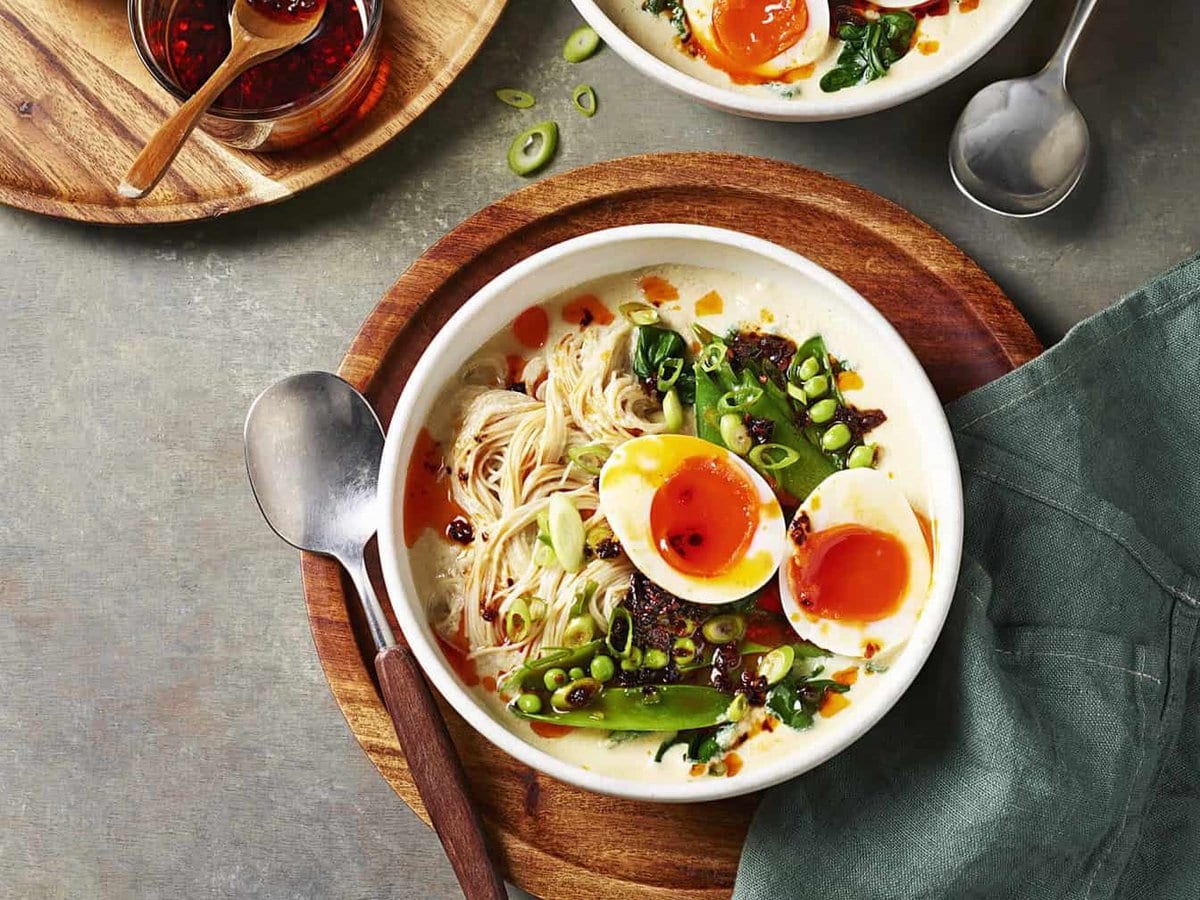 Romige misosoep met tofu en zachtgekookt eitje in een kom met een lepel