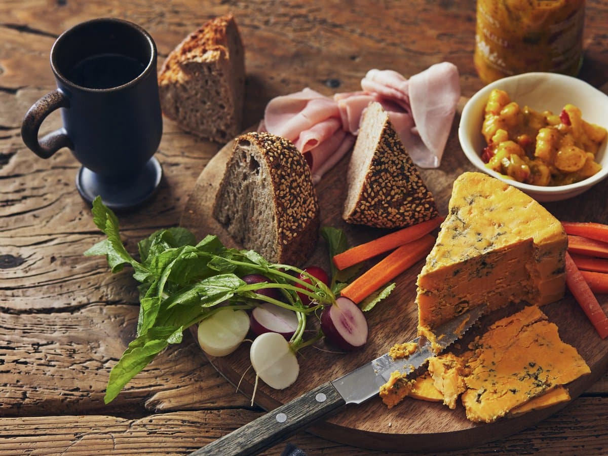 Plankje met brood, blauwe kaas, ham, wortel, radijs en piccalilly