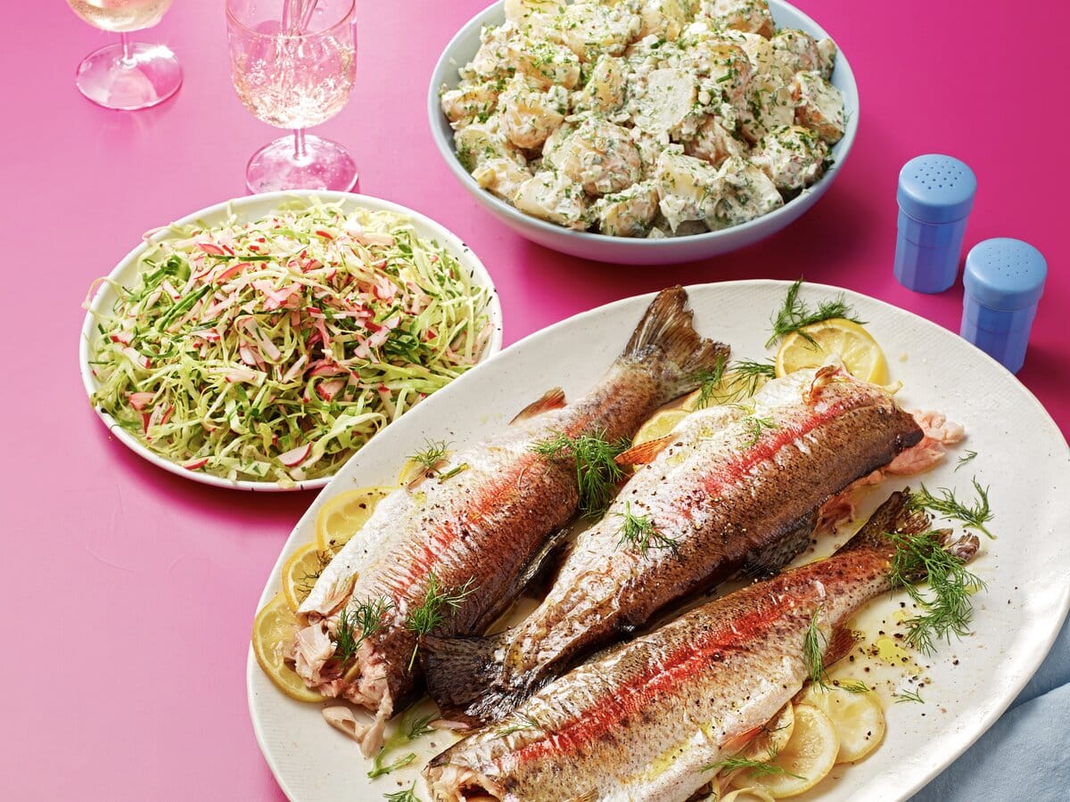 Regenboogforel met citroen en dille en daarnaast een aardappelsalade en radijssalade