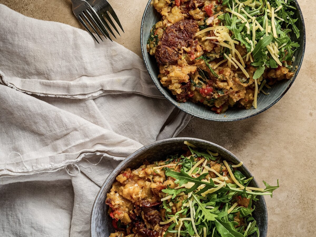Twee bakjes rucolastamppot met zongedroogde tomaat en kaas