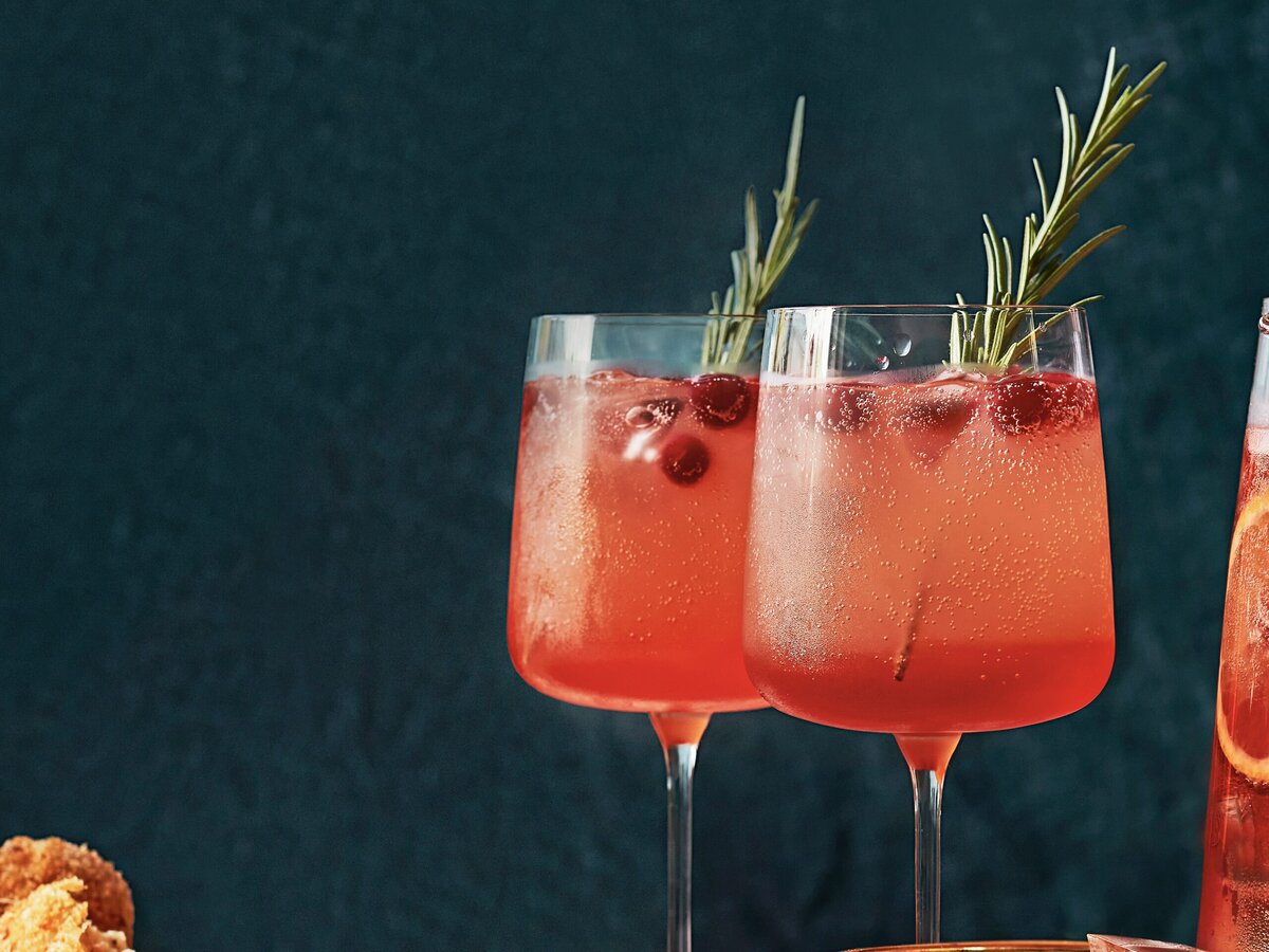 Twee Spiced Aperol spritz met een takje rozemarijn en cranberry's als garnering