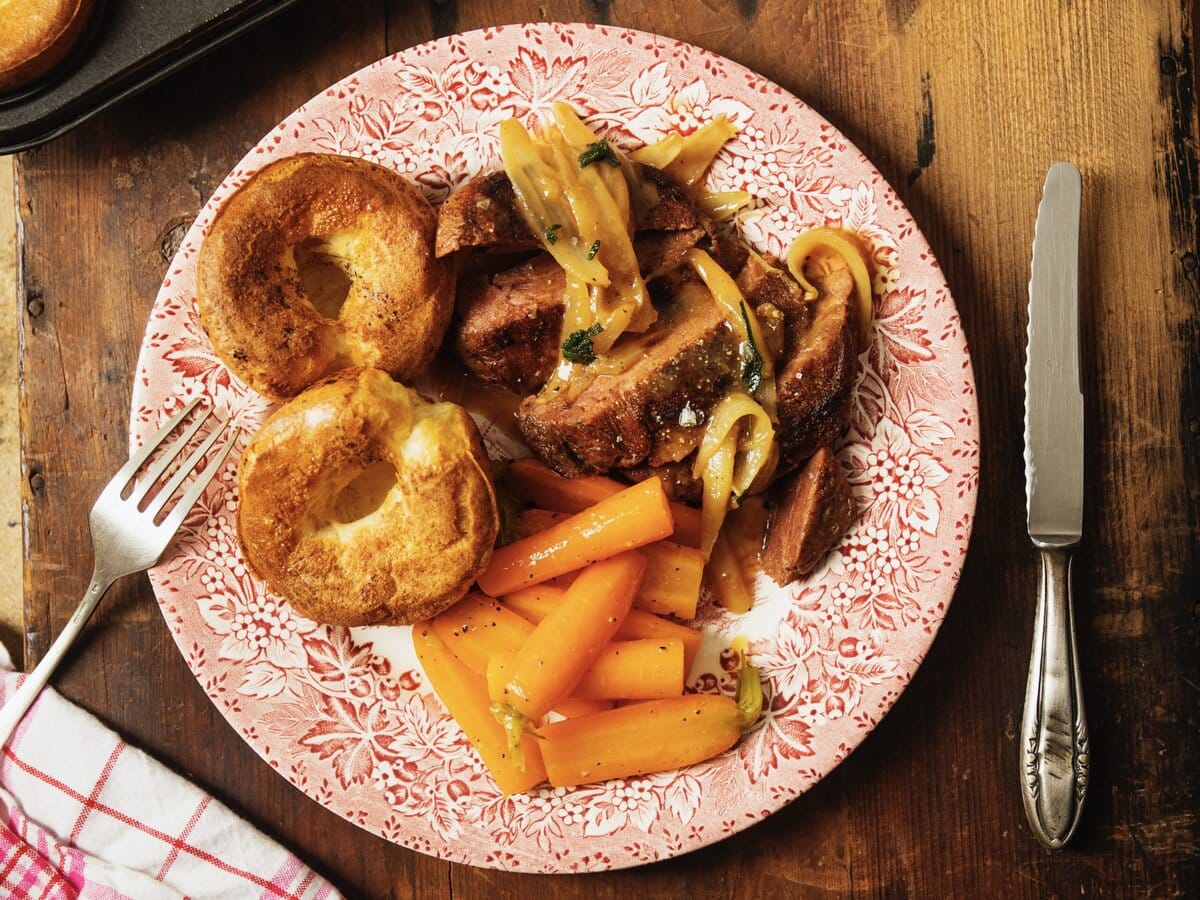 Sunday roast vlees in gebakken ui met Yorkshire puddings en gekookte worteltjes