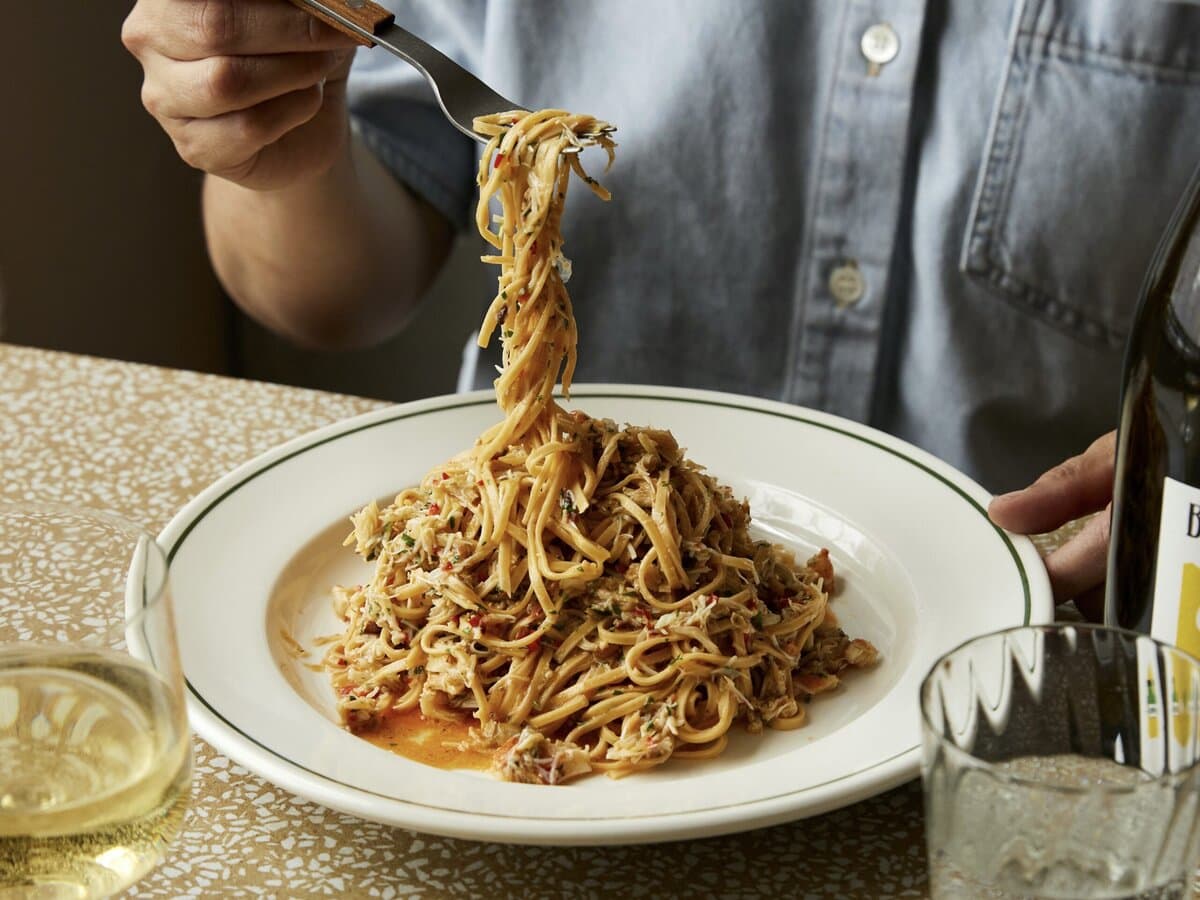 Tagliarini met venusschelpen, kerstomaten, knoflook en daarover Parmezaanse kaas