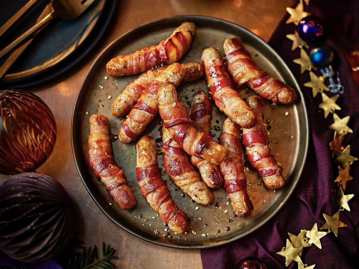 Een bord met worstjes opgerold in bacon met ahornsiroop