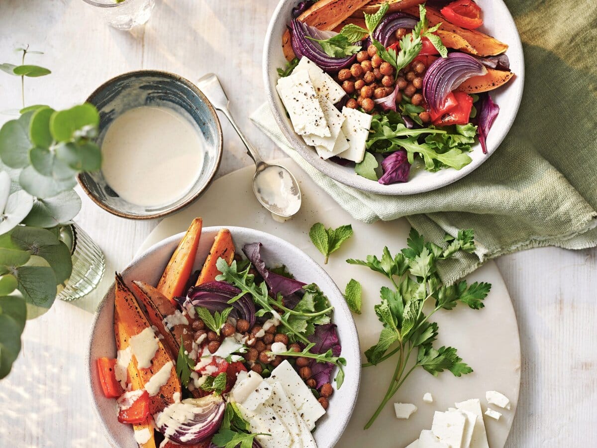 2 buddha bowls met zoete aardappel, kikkererwten, rode ui, paprika, feta, koriander en geserveerd met sausje