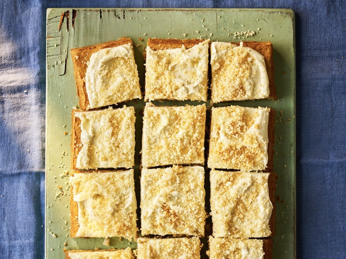 Cake met witte frosting en daarover een krokant kokos-kardemommengsel, gesneden in 12 stukken