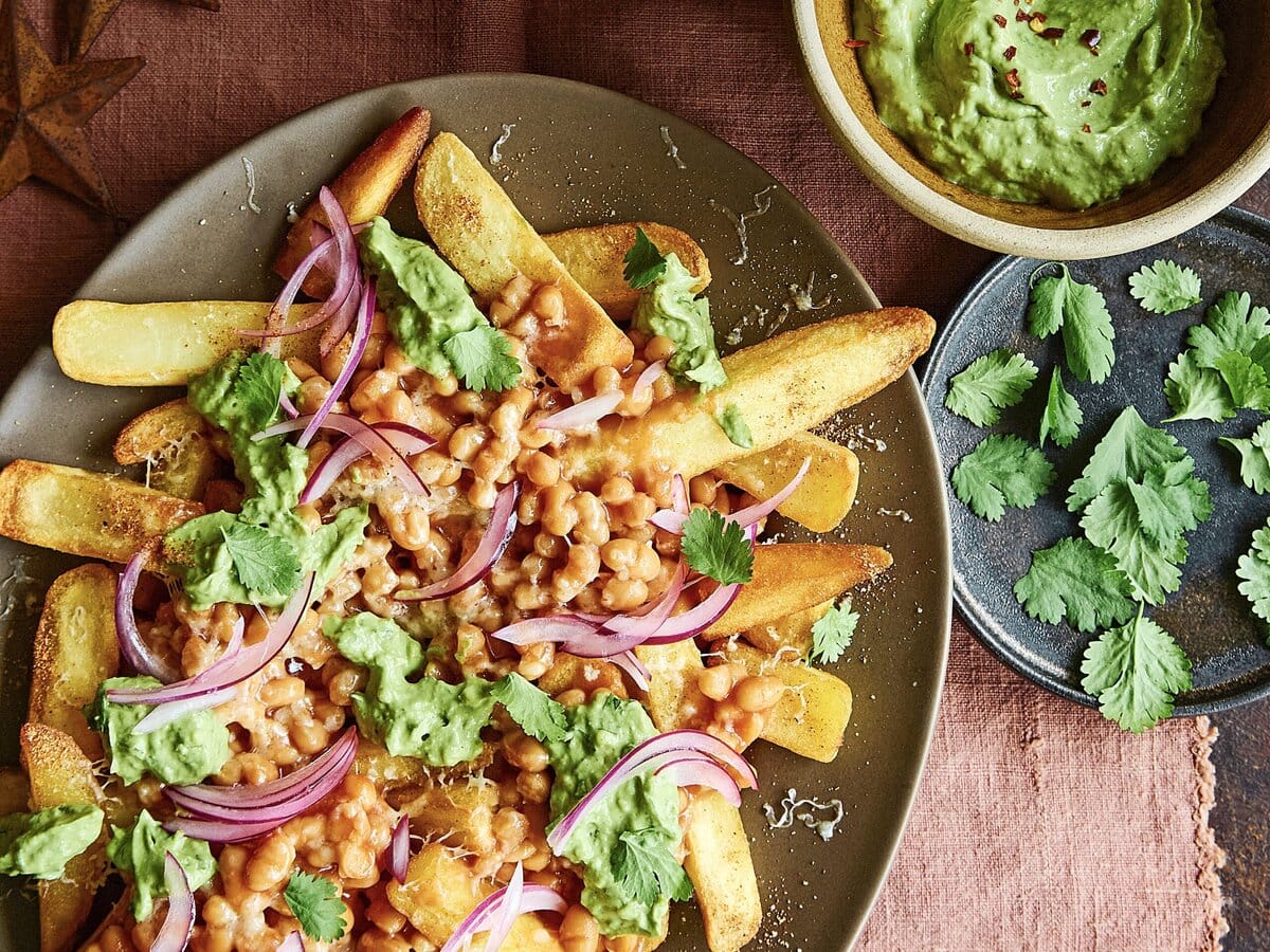 Loaded fries met chilibonen en kaas, geserveerd met koriander, rode ui en guacamole