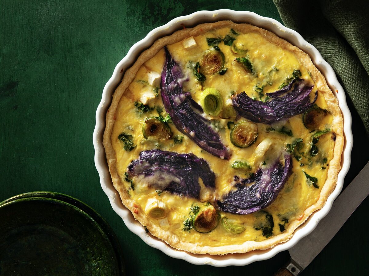 Quiche met bovenop ei en groenten, waaronder prei, spruitjes en rode kool