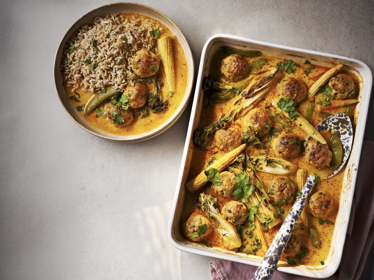 Thaise-currytraybake met kipgehaktballetjes, maïs, paksoi, peultjes en koriander, geserveerd met rijst