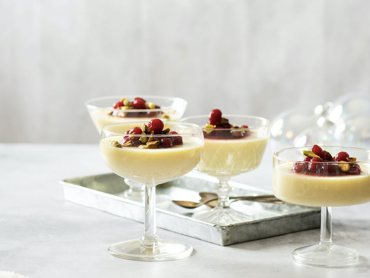 Vier glaasjes wittechocoladepanna-cotta met bovenop cranberry’s en pistache