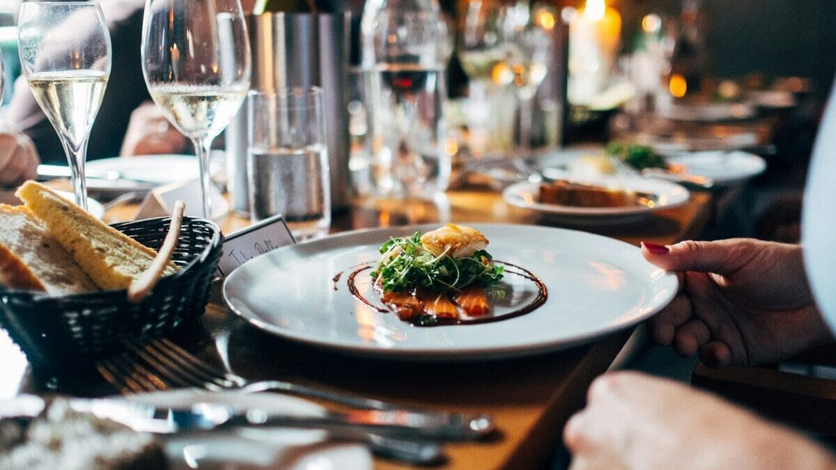 Bord met een gerecht met vis en een glas wijn bij een restaurant